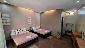 Habitación de hotel con dos camas, una mesita pequeña y una planta en maceta.