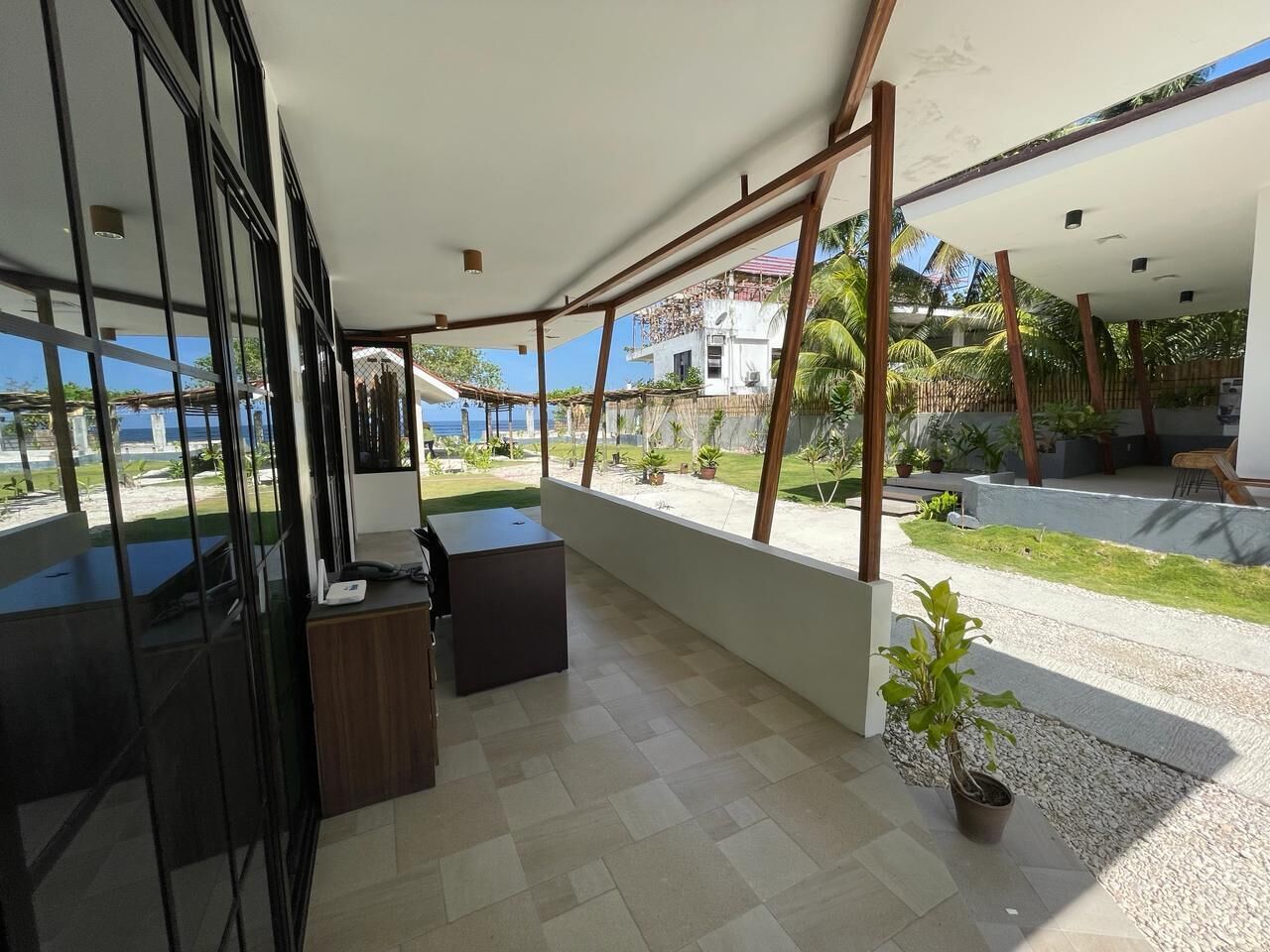Un espace extérieur moderne comprenant un comptoir d’accueil, des sièges et une vue sur la mer.