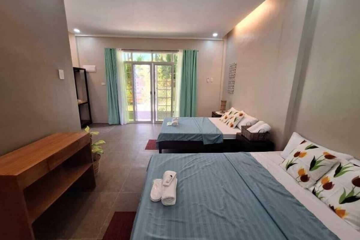 Habitació d'hotel amb dos llits, una banca i una porta corredissa de vidre que dóna a un balcó.