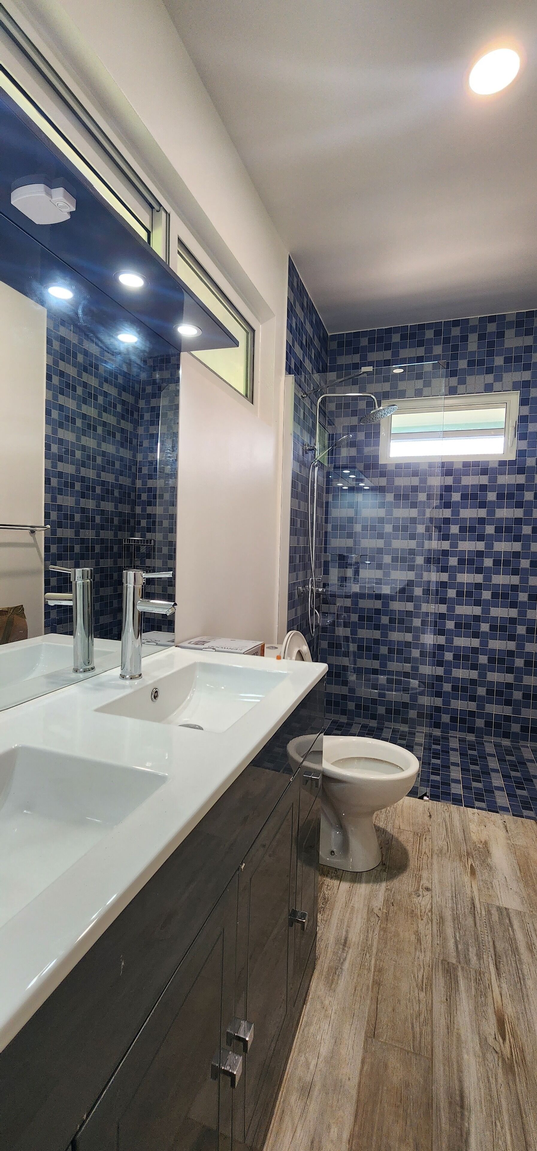 Een moderne badkamer met een groot wit wastafel, toilet en douchehoek.