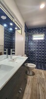 Un baño moderno con un lavamanos grande y blanco, un inodoro y una zona de ducha.