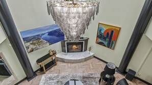 Una sala de estar moderna con chimenea, un gran candelabro y obras de arte en las paredes.