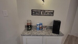 Una cocina con un letrero de estación de café, una cafetera y un molinillo de café sobre la encimera.