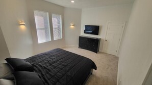 Un dormitorio con una cama grande, un televisor en la pared y un aparador.