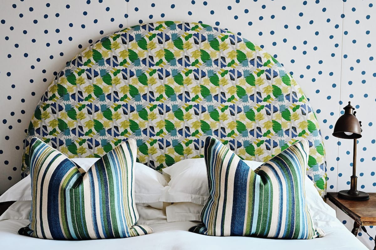 A bed with striped pillows and a patterned headboard.
