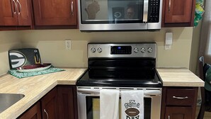 A kitchen with wooden cabinets, a stainless steel microwave, an oven, and a sink. - Walk to Lambeau! - Bart Starr 3 Bedroom house near Marquette Park, Sleeps 10 (Green Bay)