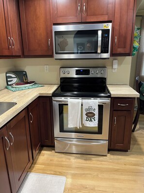 A kitchen with wooden cabinets, a stainless steel microwave, an oven, and a sink. - Walk to Lambeau! - Bart Starr 3 Bedroom house near Marquette Park, Sleeps 10 (Green Bay)