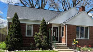 A two-story house with a brick exterior, a front porch, and a well-maintained lawn.