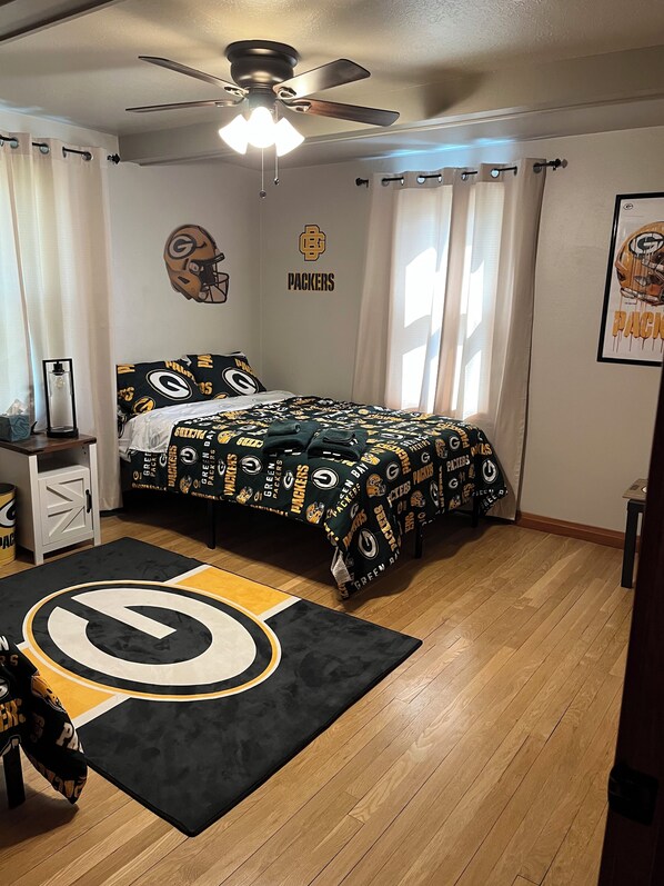 A bedroom with a bed, a ceiling fan, and a window with curtains.