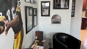 A living room with a wooden coffee table, a black armchair, and a framed sports poster on the wall.