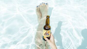 A person holding a bottle of beer with a label, standing in clear water.