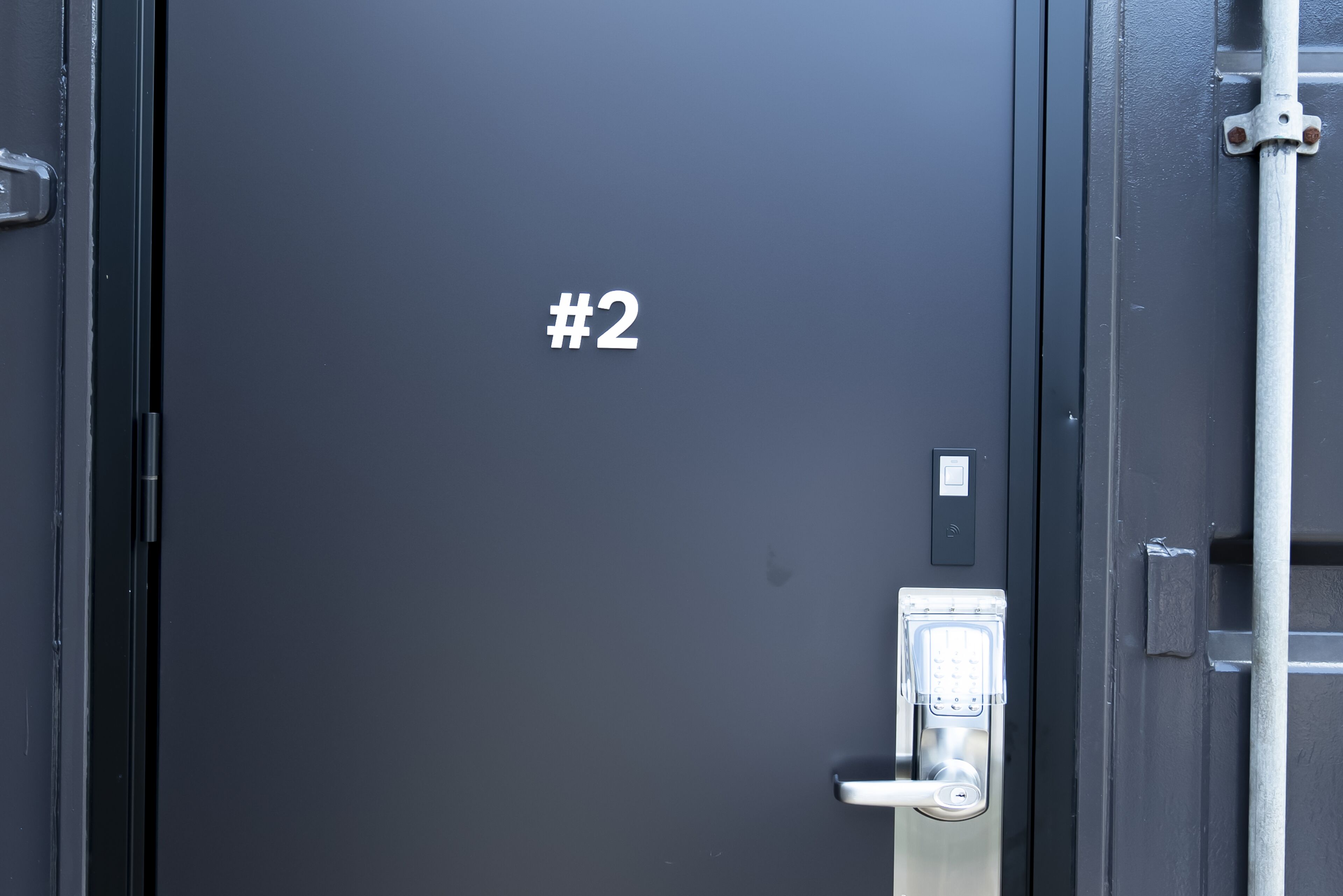 A dark door with a keypad lock and a door number sign.