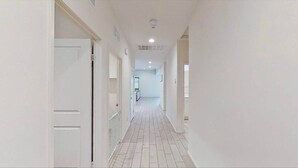 A narrow, well-lit hallway with white walls and a tiled floor, leading to a kitchen area. - The Lancaster Gem!

 (Lancaster)