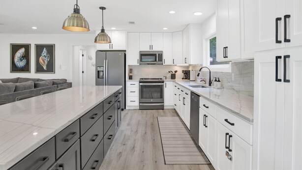 A modern kitchen with white cabinets, stainless steel appliances, and a marble countertop. - Love Shack in Foley/ Hot Tub / Modern Cozy (Foley)