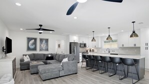 A modern kitchen with white cabinets, a central island with bar stools, and a ceiling fan. - Love Shack in Foley/ Hot Tub / Modern Cozy (Foley)