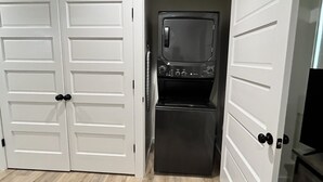 A compact kitchen with a built-in oven and microwave, white double doors, and a light-colored wooden floor. - Love Shack in Foley/ Hot Tub / Modern Cozy (Foley)