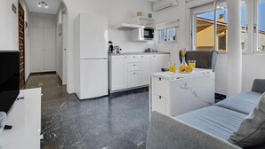 Et moderne køkken med hvide skabe, en mikrobølgeovn og en spiseplads med et bord og stole.