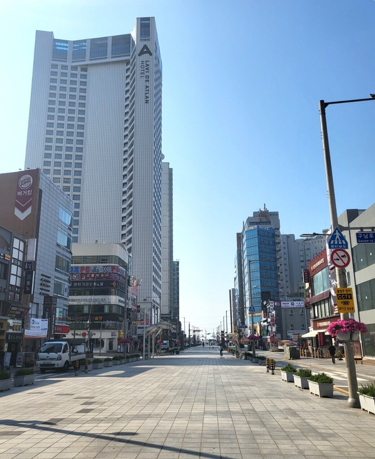Una calle urbana con edificios modernos, incluyendo un hotel con un letrero llamativo.