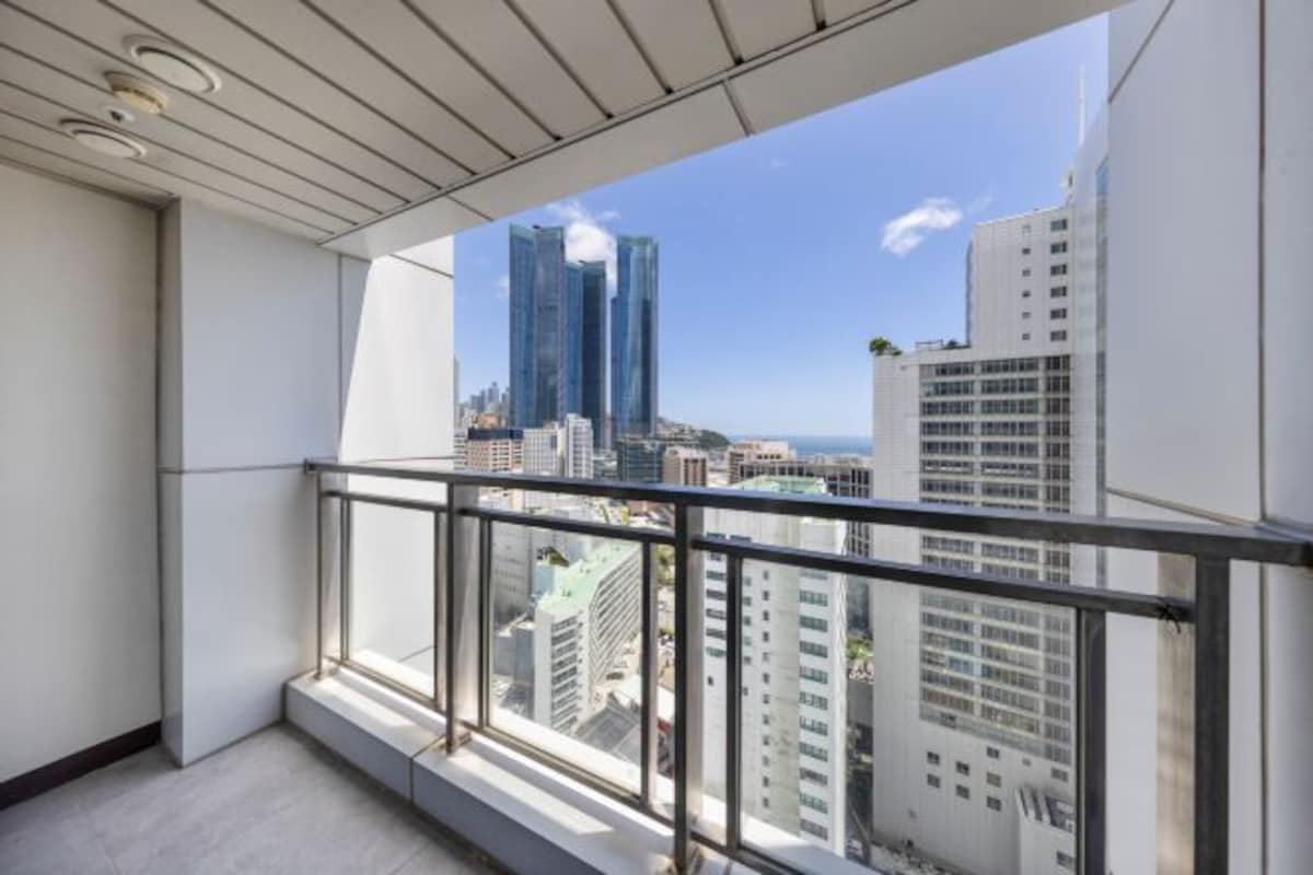 A balcony with a city view, including tall buildings and a clear sky.
