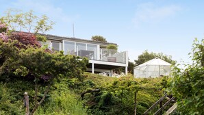 A modern house with a glass conservatory, surrounded by lush greenery. - Gorgeous home in ølsted with kitchen (Ølsted)