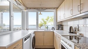 A modern kitchen with a view of the water, wooden cabinets, a dishwasher, and a stove. - Gorgeous home in ølsted with kitchen (Ølsted)