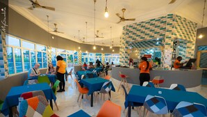 Un restaurant avec des tables et des chaises, un comptoir et un mur orné d’un motif géométrique.