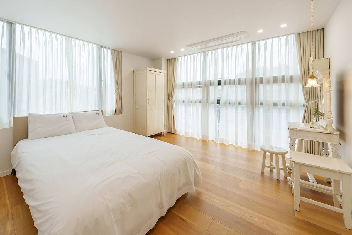 Ein geräumiges Schlafzimmer mit einem großen Bett, einer Kommode und einem Schminktisch mit Spiegel.