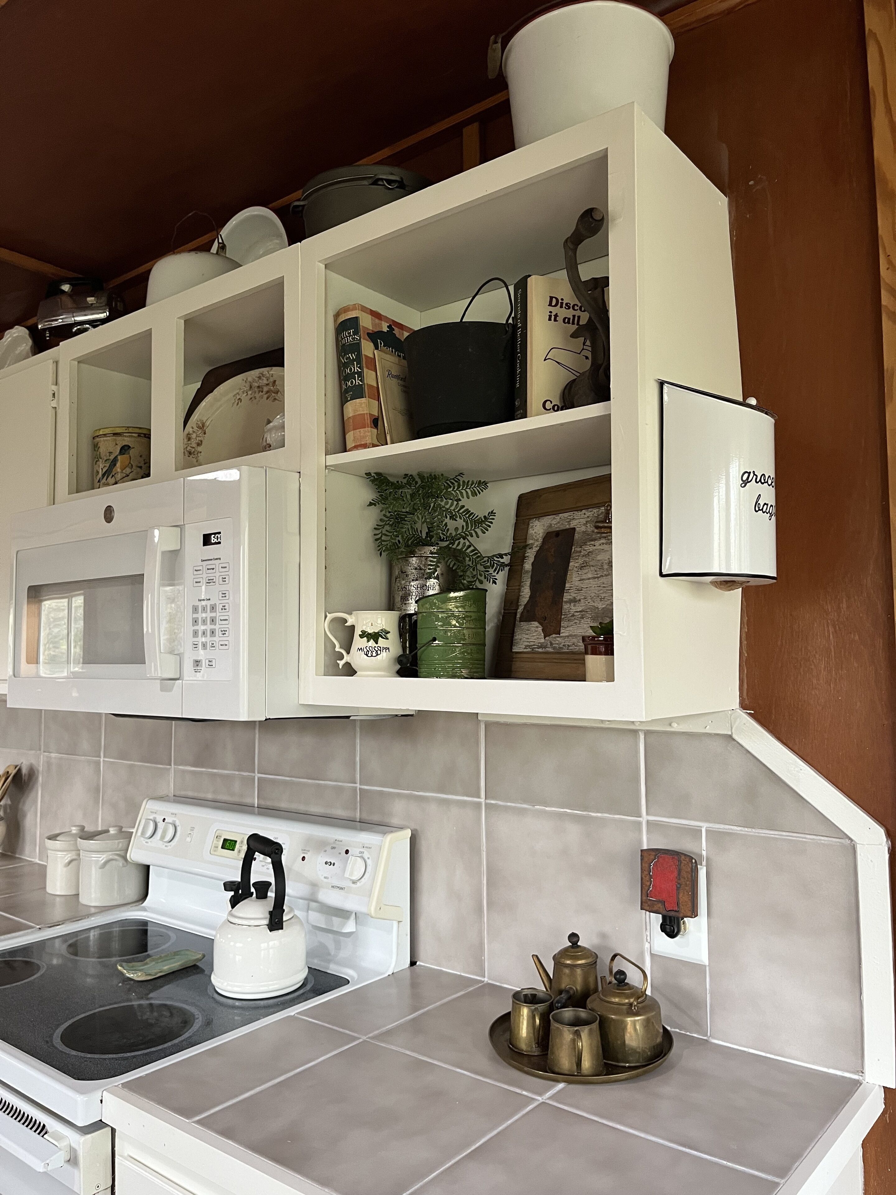 Une cuisine avec des meubles blancs, un four à micro-ondes, une cuisinière et une machine à café.