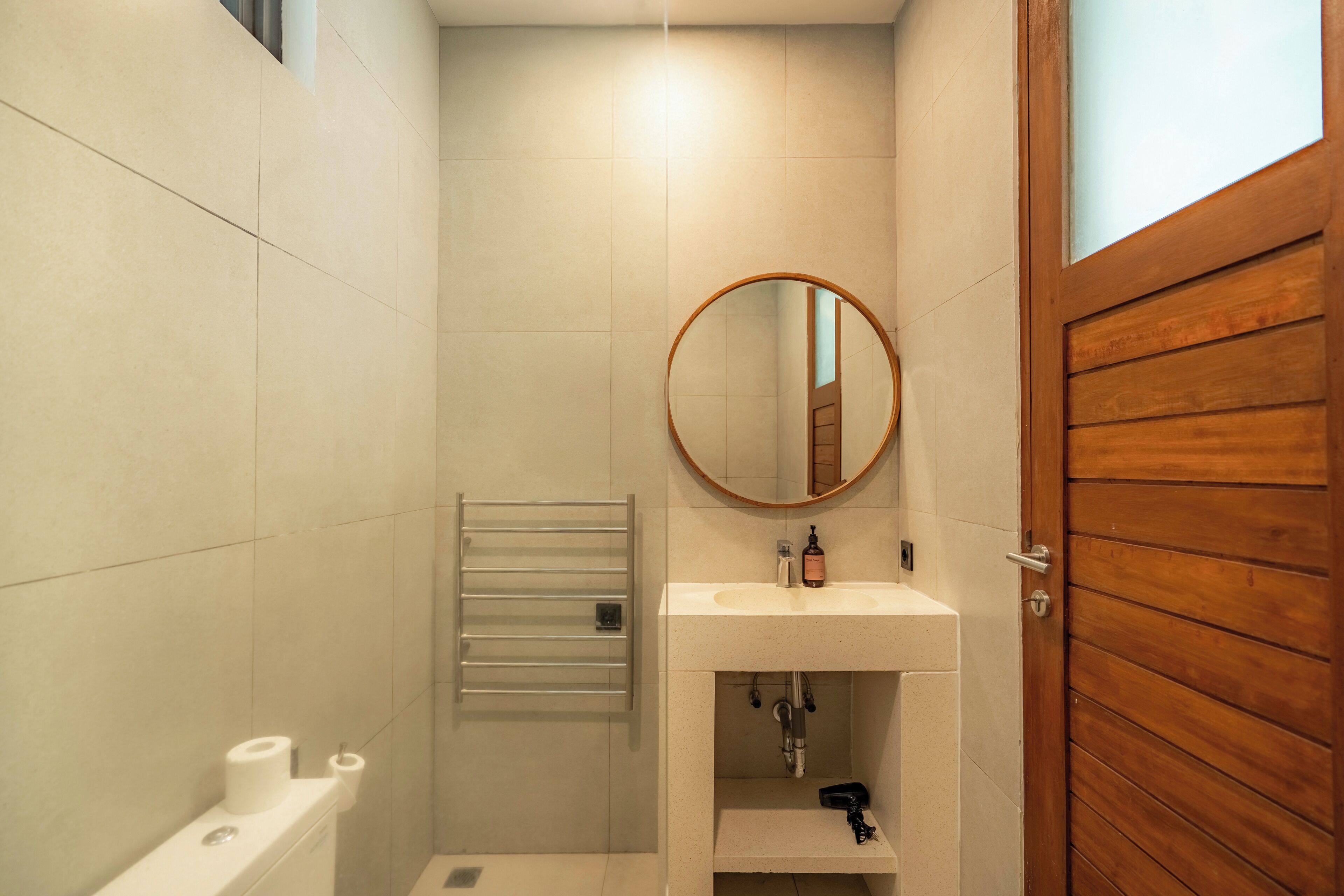 A bathroom with a white sink, a mirror, a towel rack, and a wooden door.