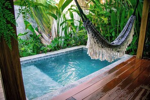 A pool with a hammock, surrounded by lush greenery.