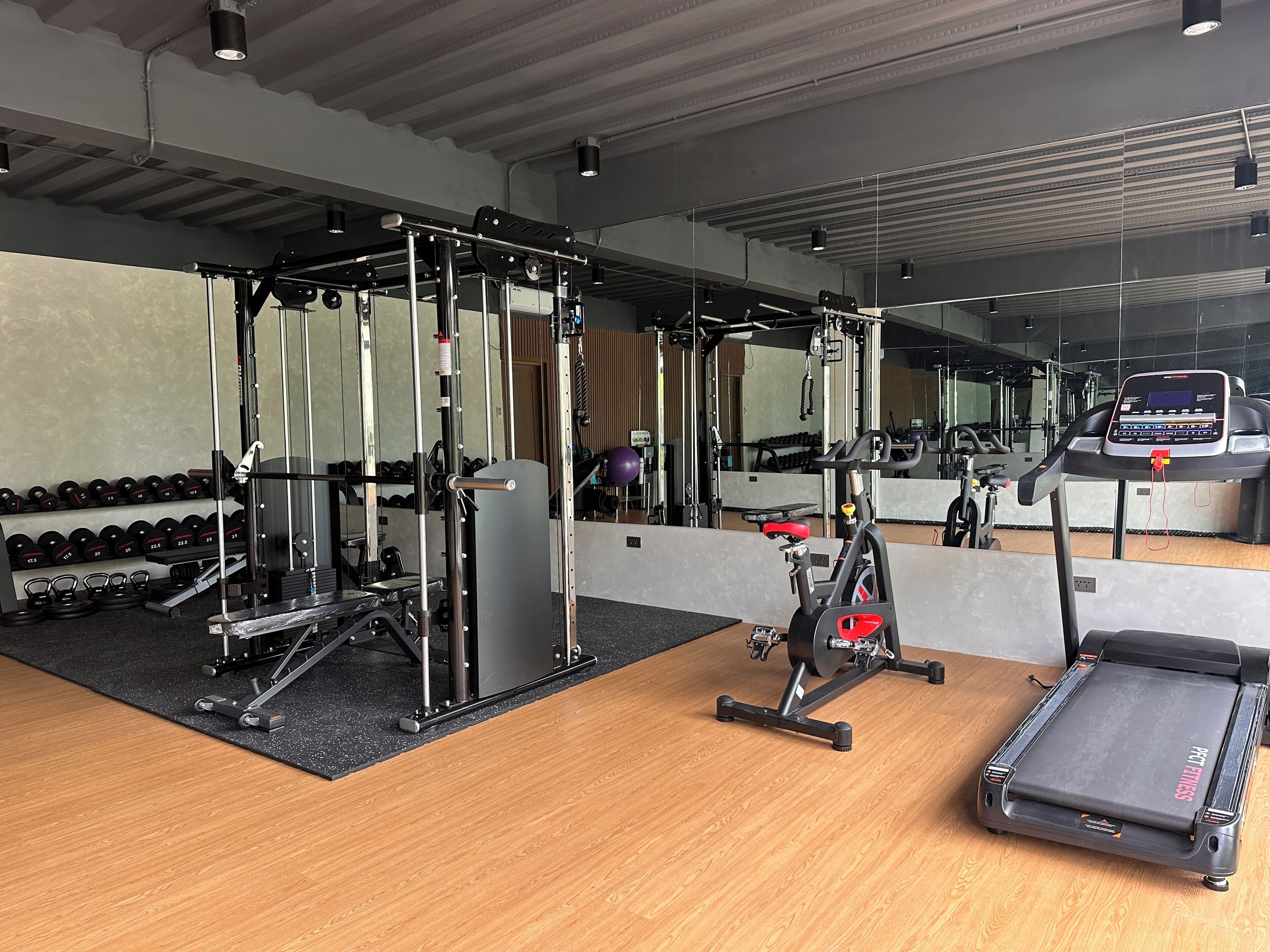 A gym with exercise equipment, a treadmill, and a mirrored wall.