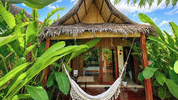 A thatched-roof hut with a hammock, surrounded by lush tropical foliage. - RECA Resort Philippines | Luxury Villas & Nature Retreat (Porac)