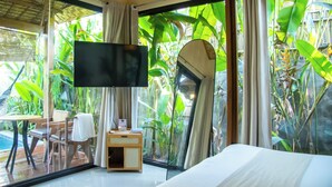 A bedroom with a large window, a bed, a TV, and a small table with chairs. - RECA Resort Philippines | Luxury Villas & Nature Retreat (Porac)