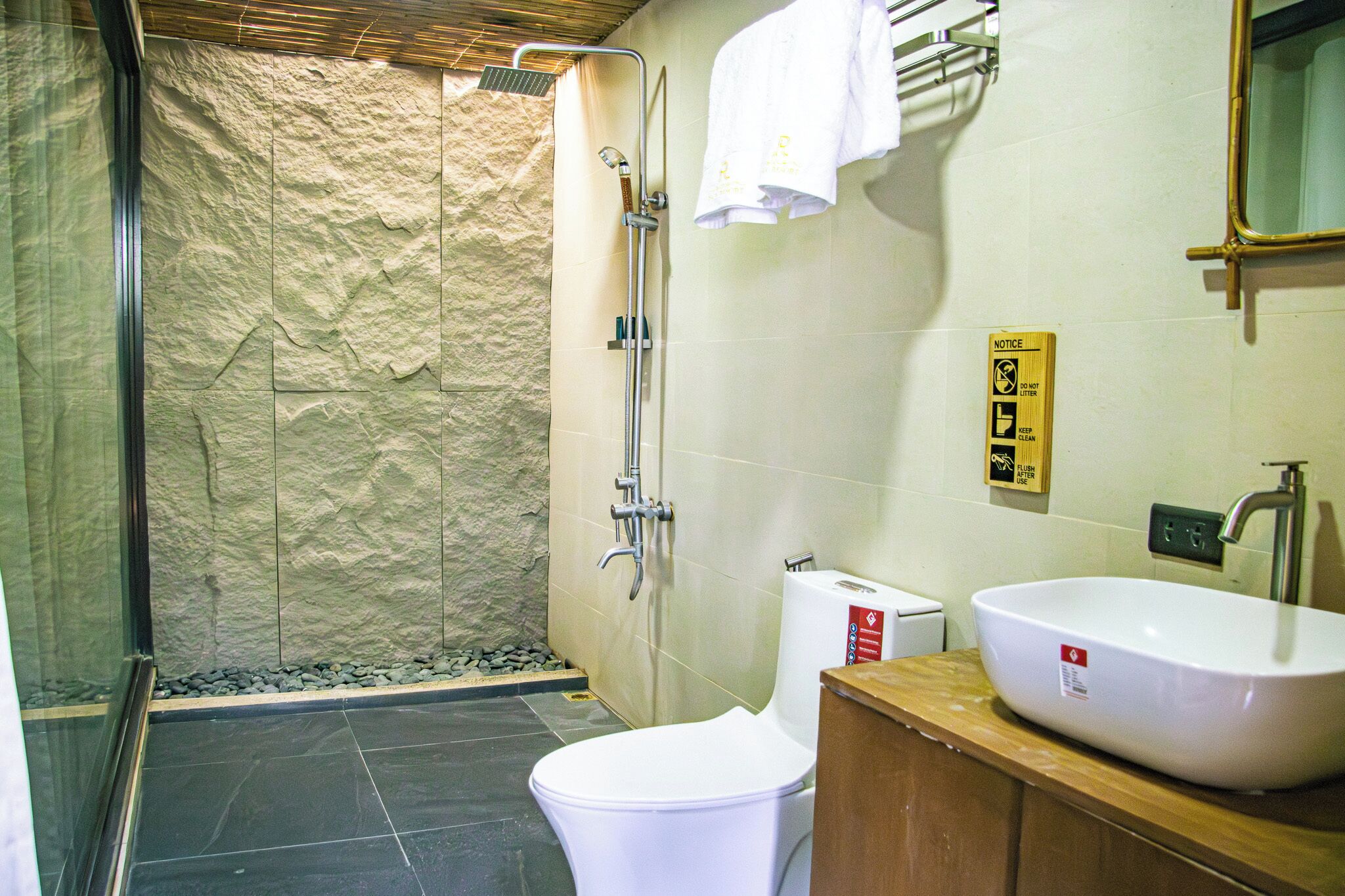 A bathroom with a shower, toilet, sink, and a textured wall.