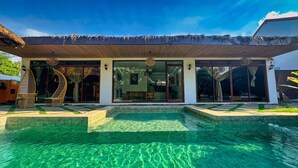 A modern house with a large glass door, a swimming pool, and a thatched roof. - RECA Resort Philippines | Luxury Villas & Nature Retreat (Porac)