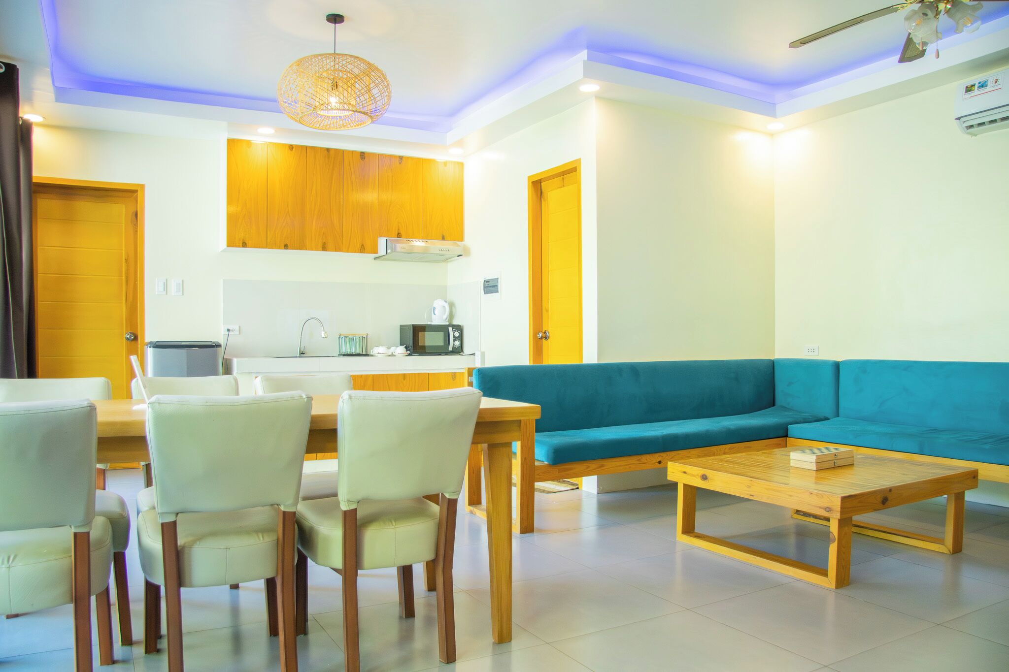 A modern living room with a sofa, a coffee table, and a dining area with chairs and a table.