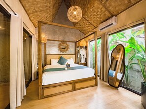 Un dormitorio espacioso con una cama grande, techo de madera y vistas a exuberante vegetación.