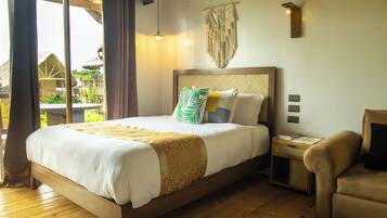A bedroom with a large bed, a nightstand, a chair, a macrame wall hanging, and a view of the outside.