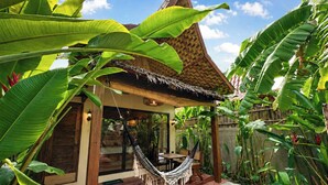 A poolside area with a hammock, wooden deck, and lush tropical plants. - RECA Resort Philippines | Luxury Villas & Nature Retreat (Porac)