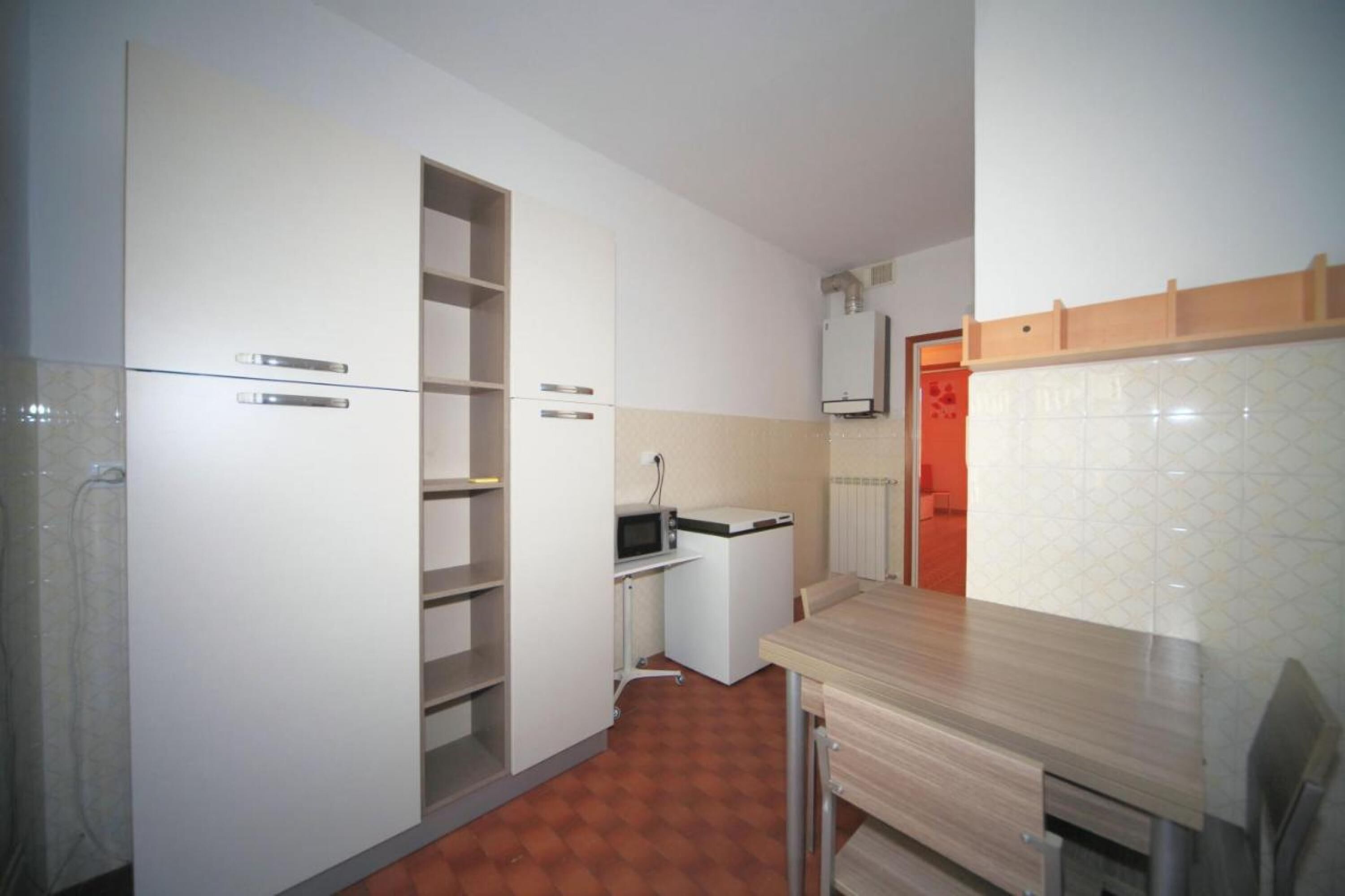 Een kleine keuken met witte kasten, een magnetron en een klein aanrecht.