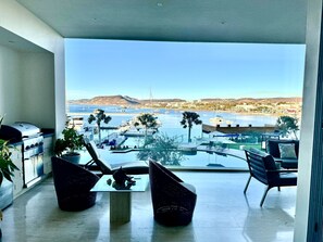 Un balcon offrant une vue sur un port de plaisance, une piscine et une montagne au loin.