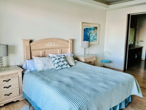 Cama bem arrumada com colcha listrada, cabeceira de madeira e mesas de cabeceira combinando com gavetas.