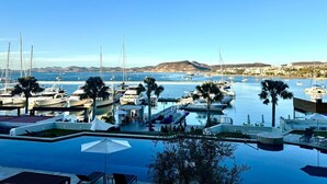 Un puerto deportivo con barcos, piscina y vistas a la costa.