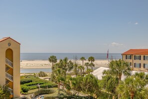 Un hôtel avec vue sur la plage, les palmiers et un drapeau.