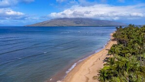 Una playa con aguas azul turquesa, una orilla arenosa y una montaña al fondo.