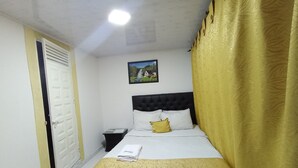 A bedroom with a bed, a nightstand, a door, and a painting on the wall. - NINI nini (Bogotá)