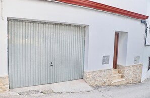 A building with a large metal garage door, a small window, and a stone base. - Apartment Reyes, in Conil de la Fra. (Conil de la Fra.)