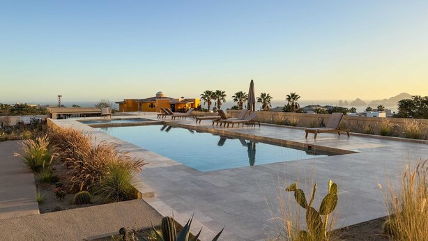 A pool area with lounge chairs, a building with a yellow facade, and palm trees. - Casa Kavita Mistiq | El Tezal Luxury Penthouse Condo (El Tezal)