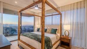 A four-poster bed with a city view, a bedside table with a lamp, and sheer curtains. - Casa Kavita Mistiq | El Tezal Luxury Penthouse Condo (El Tezal)