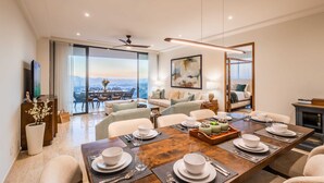 A modern dining area with a large table set for six, a sofa, and a balcony with a city view. - Casa Kavita Mistiq | El Tezal Luxury Penthouse Condo (El Tezal)